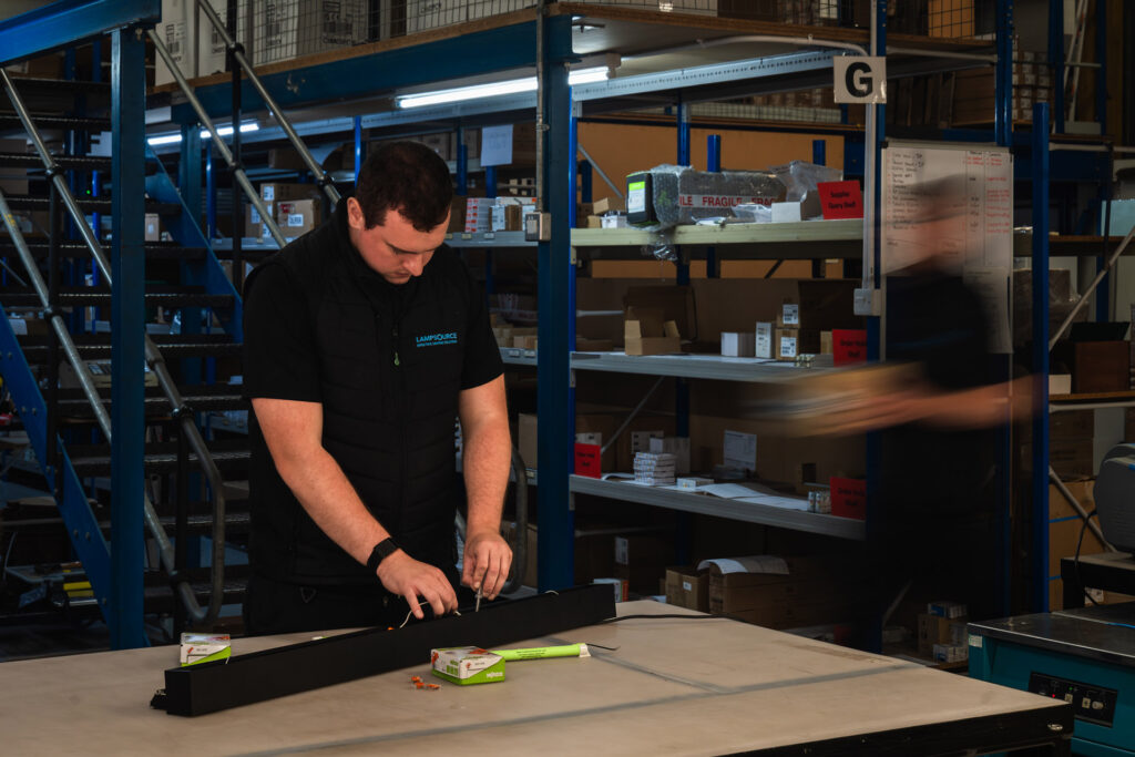 Technician assembling a lighting unit in the Lampsource Project Solutions warehouse.