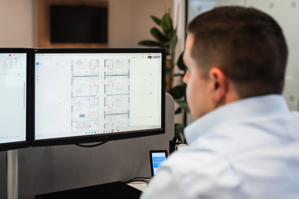 Professional at Lampsource Project Solutions analysing building lighting layouts on dual monitors.