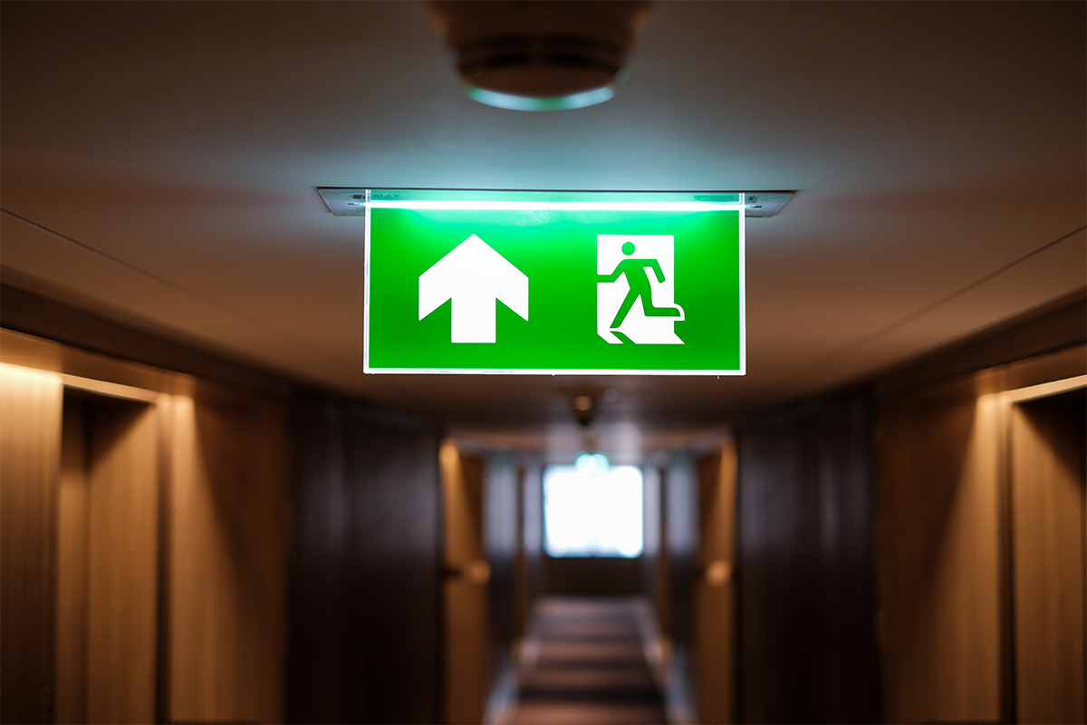 Illuminated green emergency exit sign hanging in a corridor